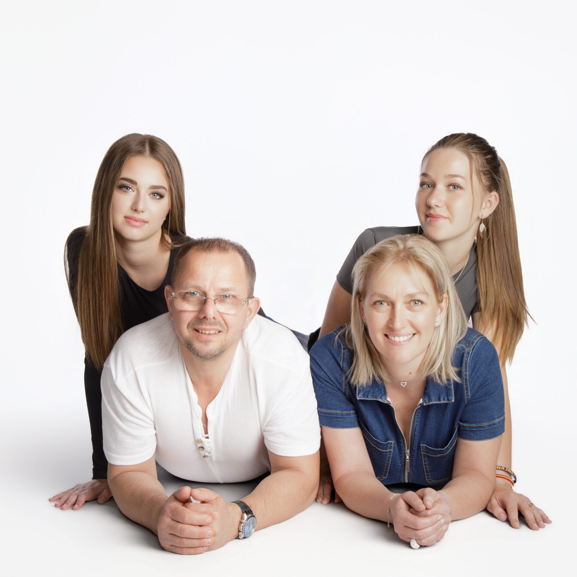 Portrait de famille en studio sur fond blanc : couple allongé au premier plan, deux adolescentes posant derrière eux au Studio Salvucci, Photographe, Metz
