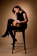 Portrait de femme pensive en noir sur tabouret en bois photographiée par le Studio Salvucci à Metz.