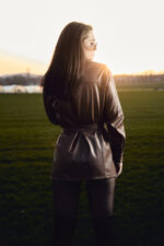 Femme en veste cuir au coucher de soleil dans un champ photographiée par le Studio Salvucci à Metz