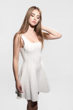 Jeune femme en robe blanche perlée, pose élégante.