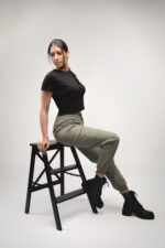 Femme en crop top noir, pantalon cargo vert, bottes assise photographiée par le Studio Salvucci à Metz.